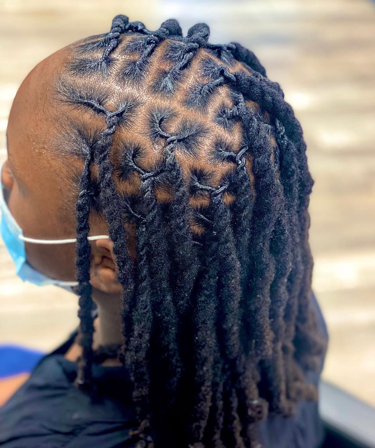 Client with neat locs and geometric parting